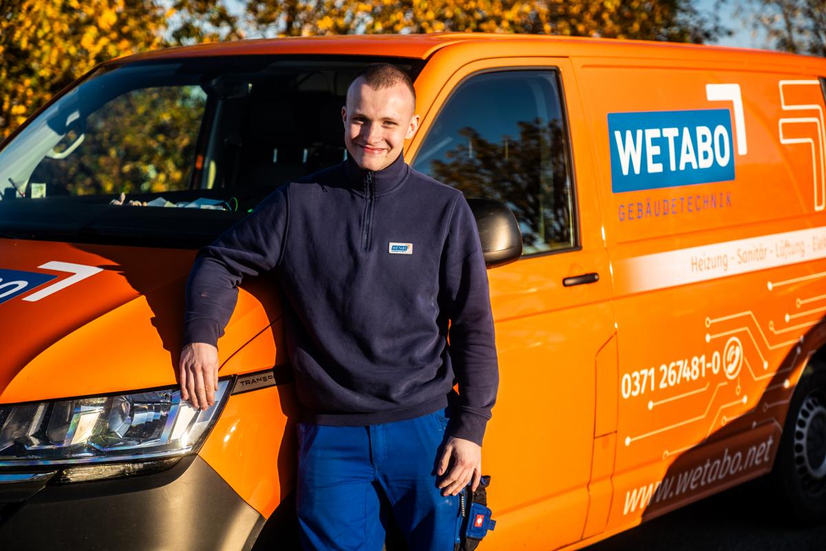 WETABO-Monteur am orangen Firmentransporter